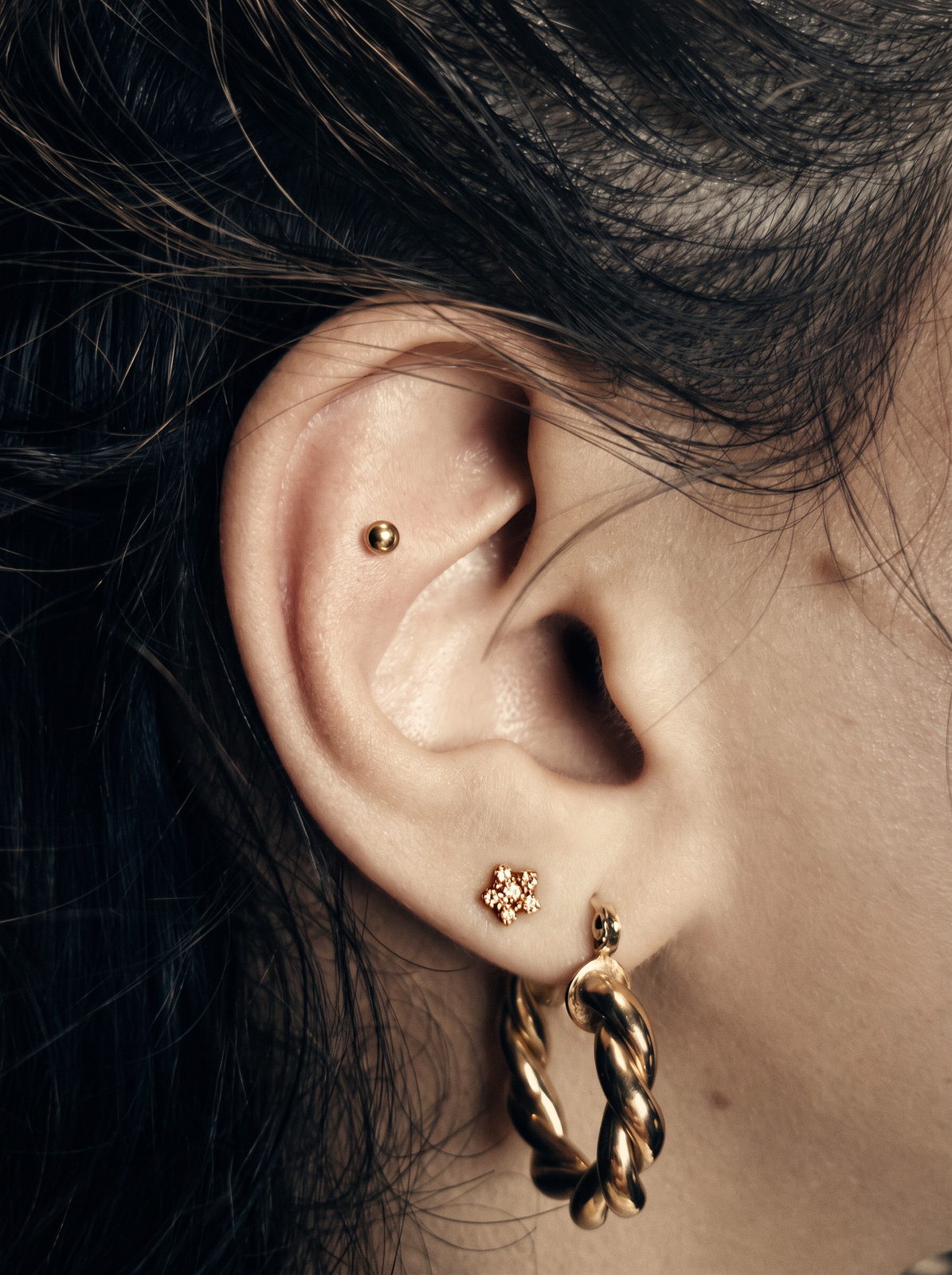 Helix- und Lobe-Piercings mit Goldschmuck im Detail