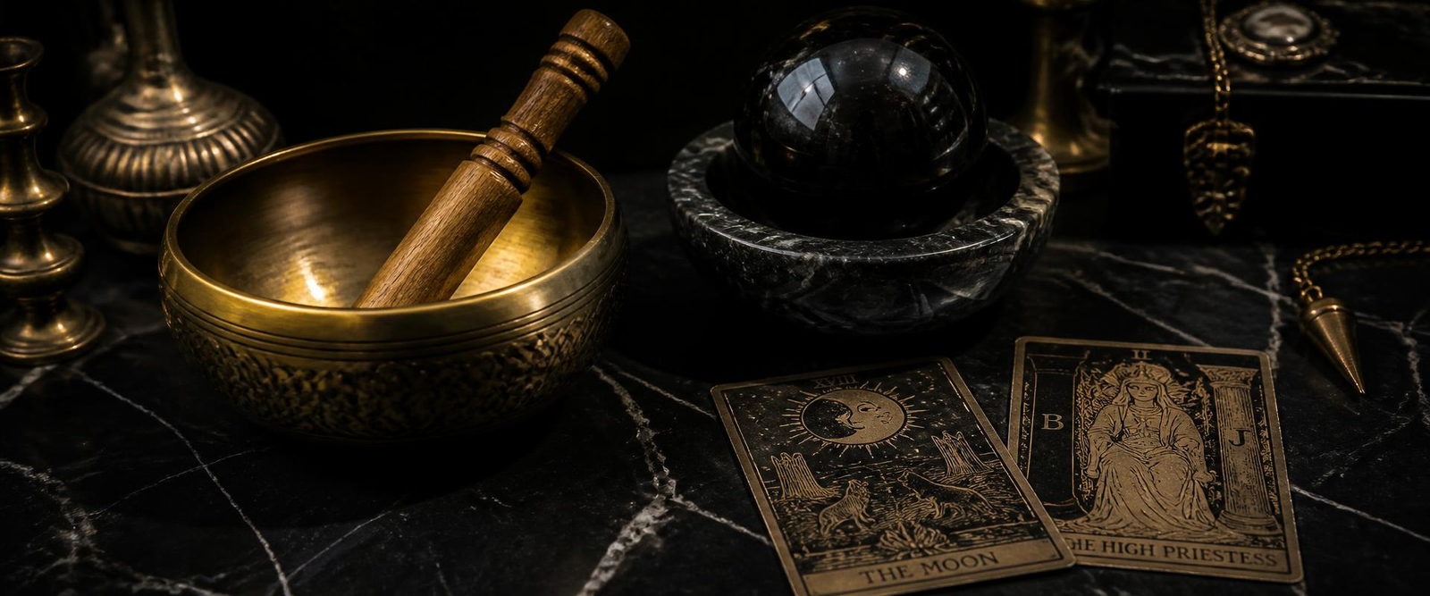 Klangschale, Obsidiankugel und Tarotkarten auf schwarzem Marmor